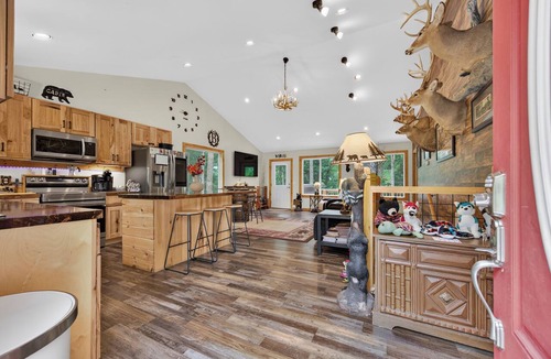 Galax House | A secluded, multi-level log cabin featuring a spacious wooden deck, open-concept living, a fully equipped modern kitchen, and comfortable sports-themed bunk rooms.