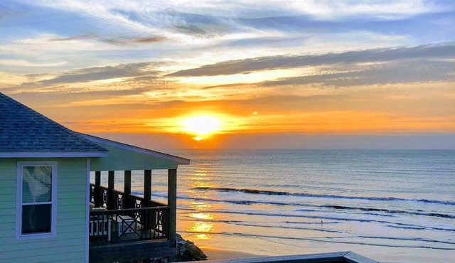 Martinis & Bikinis, a beach front house with toes in the sand drink in the hand.